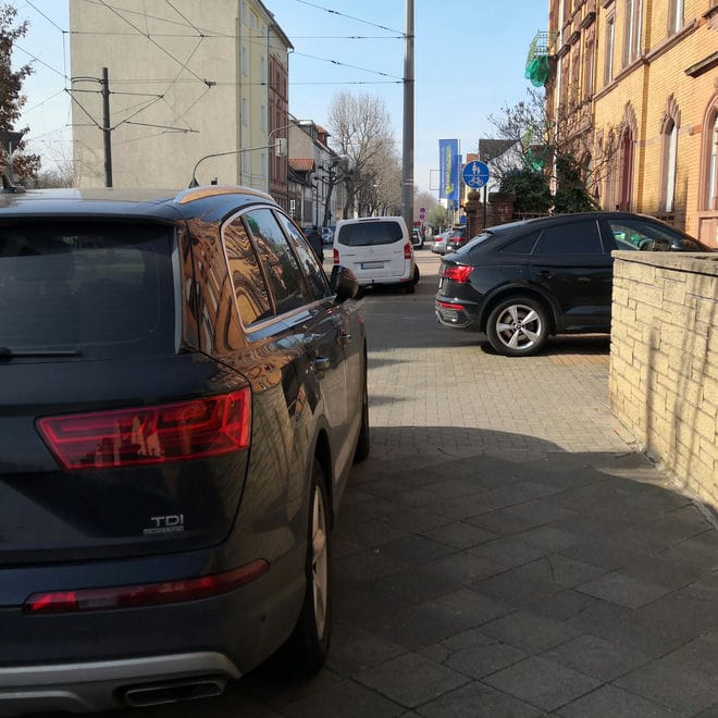 Ein gemischter Weg für Fußgänger und Radfahrer, gekennzeichnet mit Zeichen 240, von Straßen- und Gebäudeseite zugeparkt mit Autos.